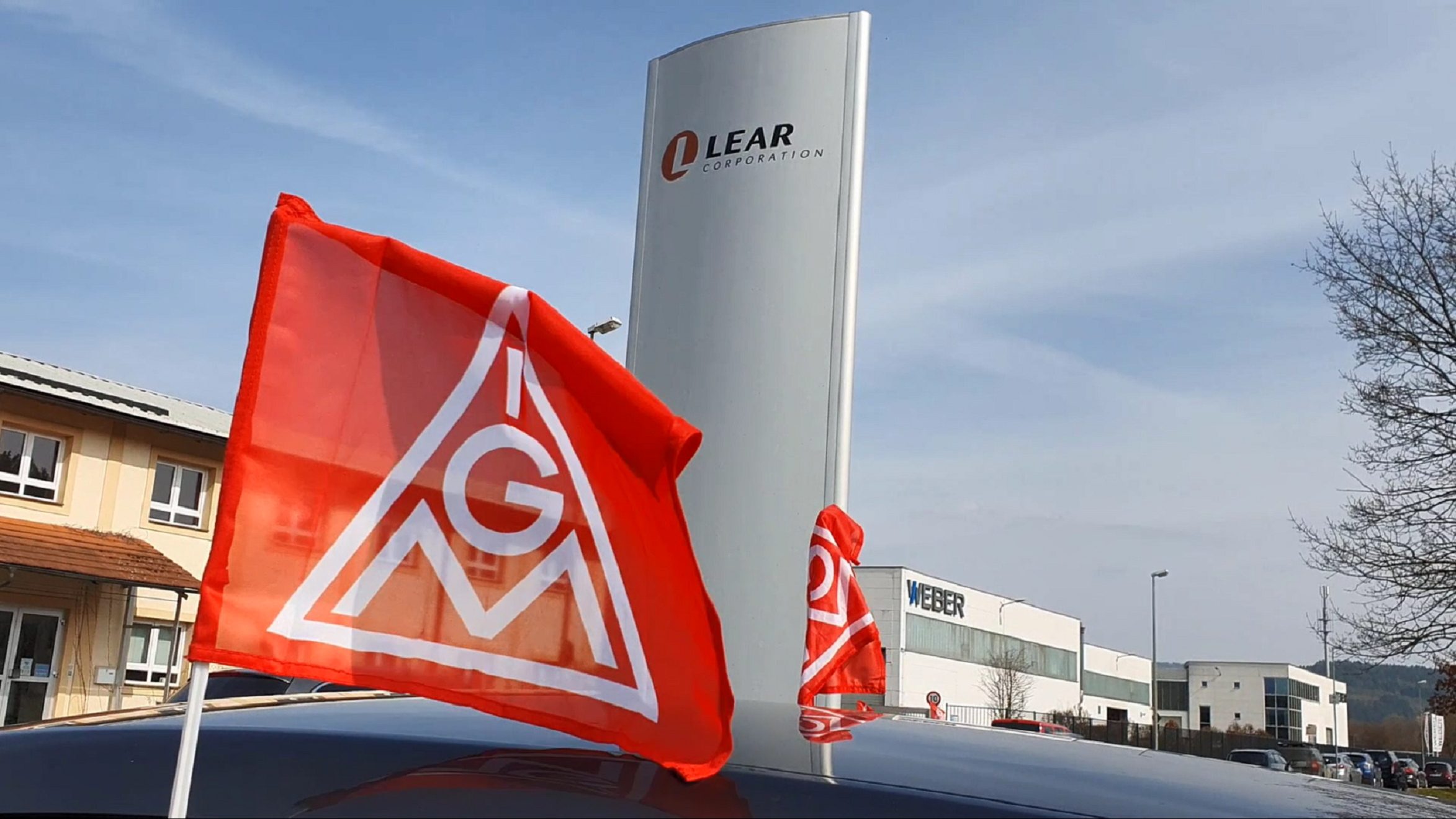 Eine IG Metall Fahne vor dem Lear-Firmenlogo am Standort Kronach