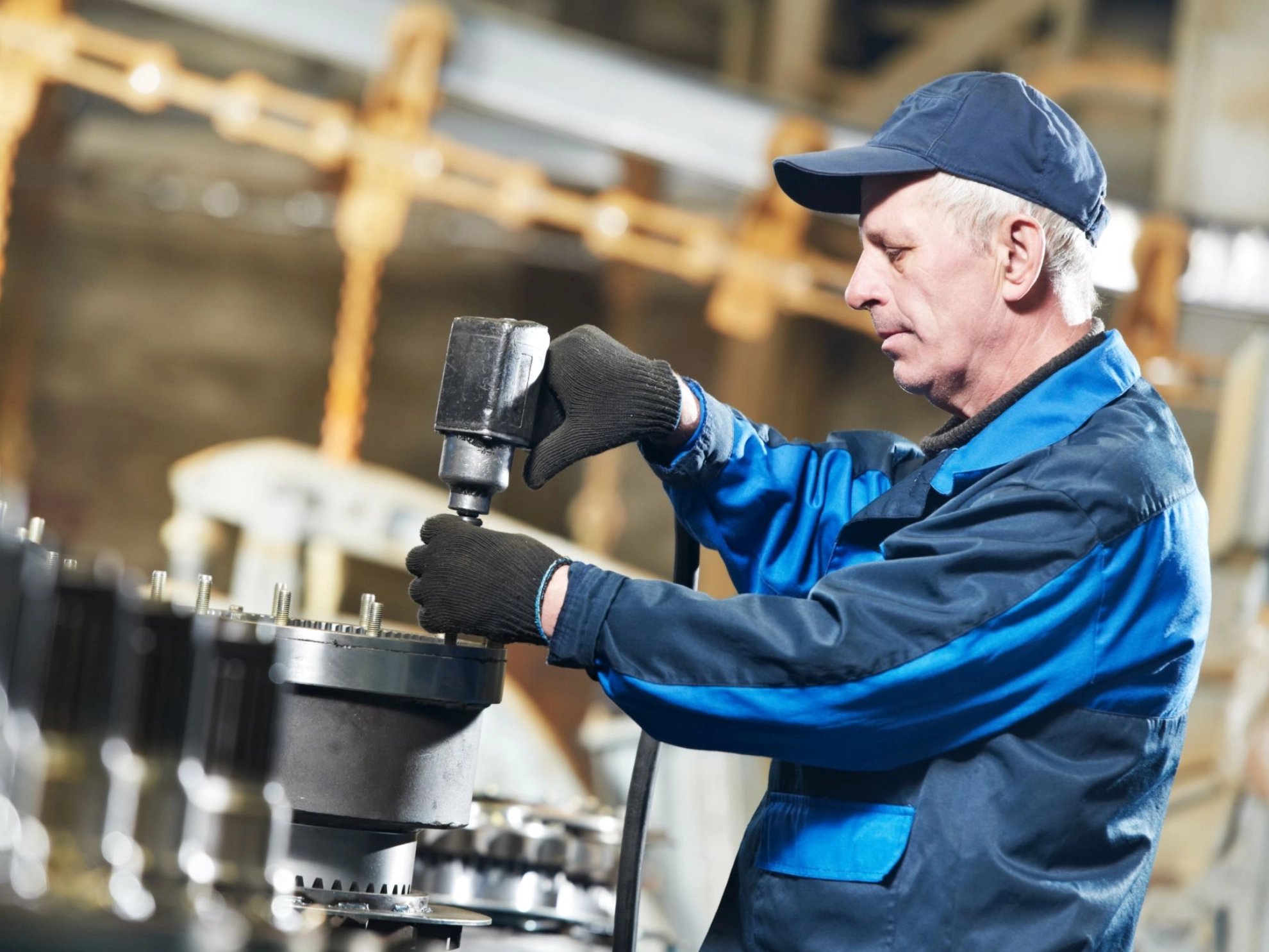 älterer Beschäftigter mit Akkuschrauber in Fabrik