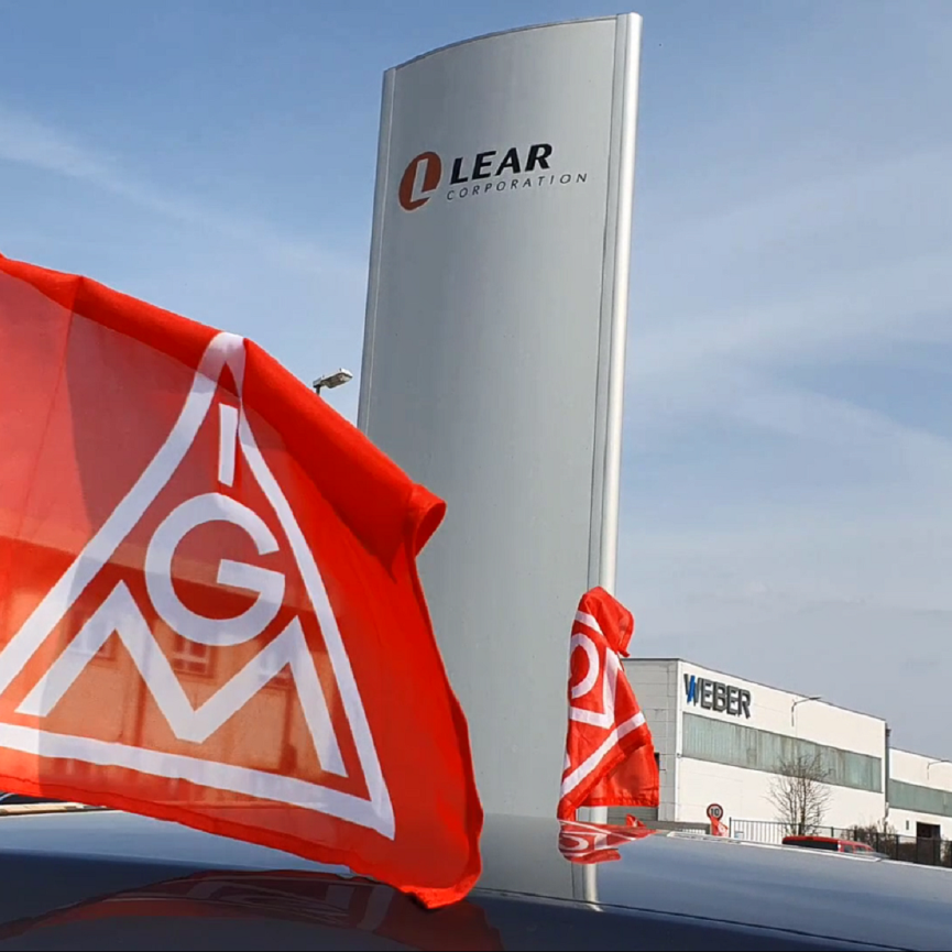 Eine IG Metall Fahne vor dem Lear-Firmenlogo am Standort Kronach