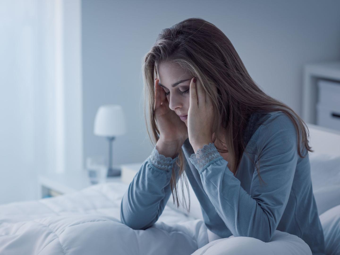 junge Frau sitzt müde in ihrem Bett