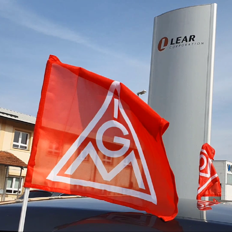 Eine IG Metall Fahne vor dem Lear-Firmenlogo am Standort Kronach